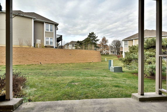 View of apartment buildings and grassy area with trees and shrubs.