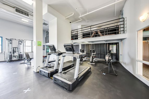 Interior view of a gym with exercise equipment including treadmills and weight machines.