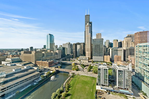 Panoramic view of a cityscape featuring numerous tall buildings and a river.