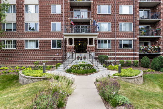 Front view of a multi-story brick apartment building with a central entrance and balconies.