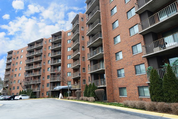 Front view of a multi-story brick apartment building with balconies.