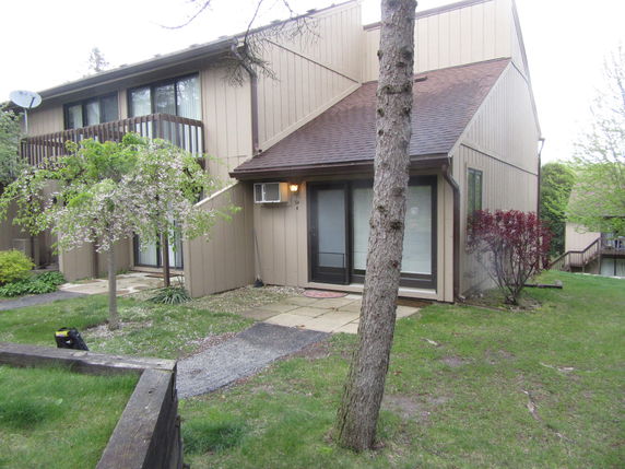 Front view of a two-story house with a balcony and sloped roof.