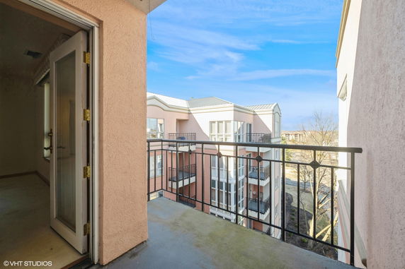 View from a balcony overlooking nearby buildings with balconies and large windows.
