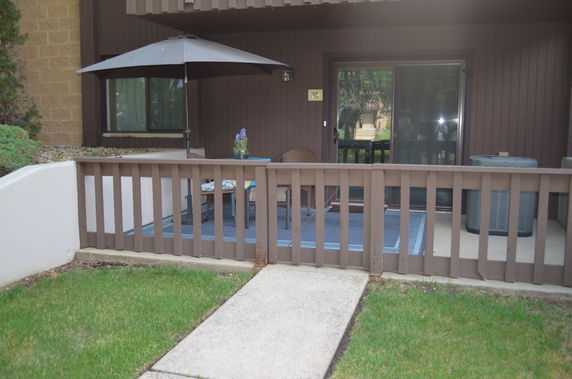 Front view of an outdoor patio area with a sliding glass door and patio furniture.