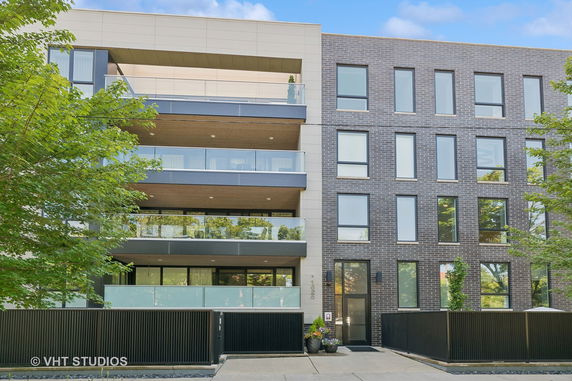 Front view of a modern multi-story building with balconies and large windows.