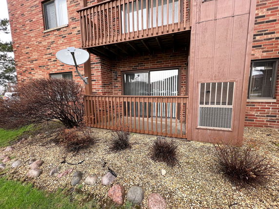 Front view of a brick building with balconies and a satellite dish.