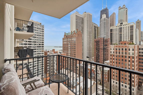 Balcony view of cityscape with tall buildings and distant lake.
