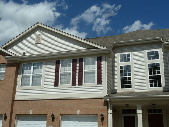 Front view of a multi-story house with large windows and brick facade.