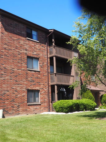 Front view of a multi-story brick apartment building with balconies.
