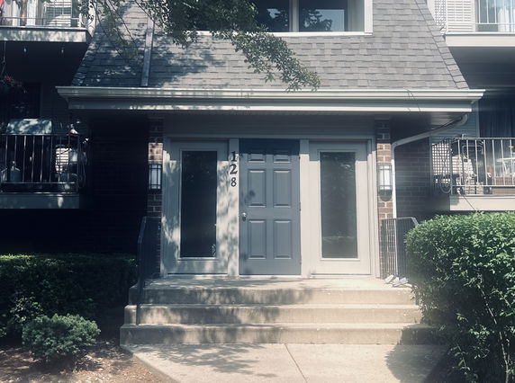 Front view of a building entrance with a gray door and adjacent windows.