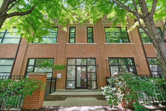 Front view of a brick residential building with large windows.