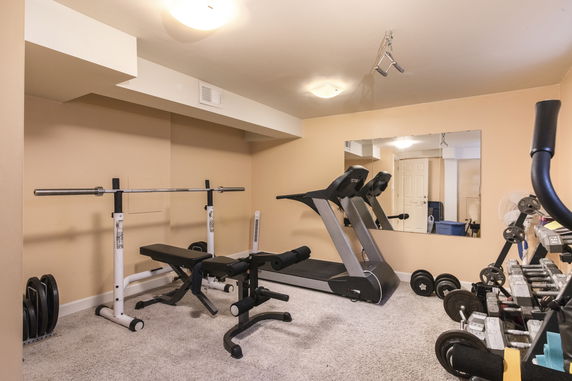 Indoor gym area with exercise equipment including treadmill and dumbbells.