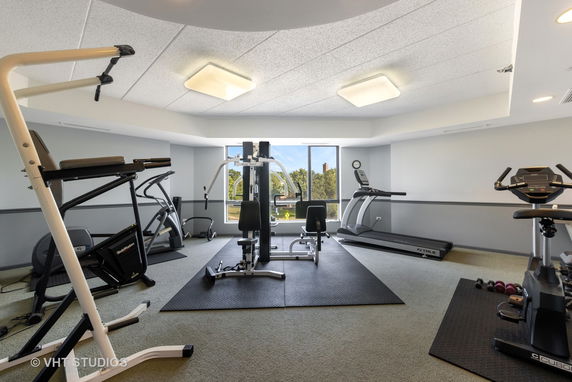 Room equipped with various exercise equipment including treadmills and stationary bikes.