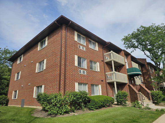 Front view of a multi-story brick apartment building with small balconies.