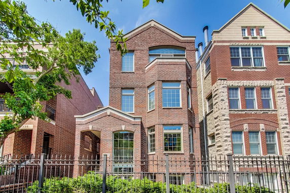 Front view of a multi-story brick townhouse with large windows.
