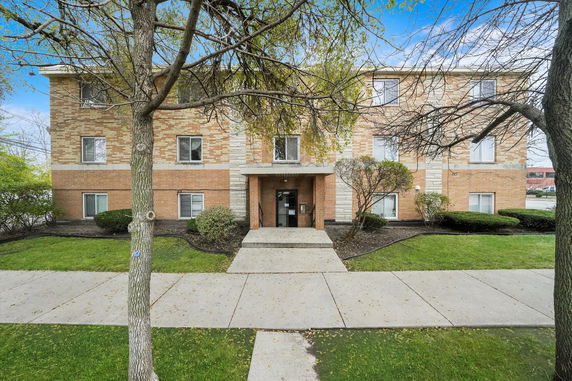 Front view of a three-story brick apartment building with multiple windows.