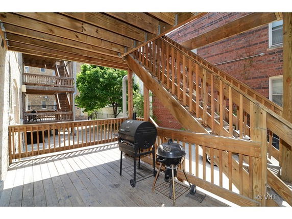 Wooden rooftop with staircases and two barbecue grills.