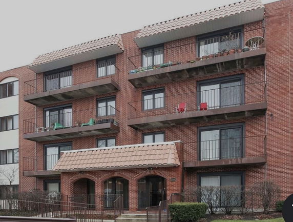 Front view of a multi-story brick apartment building with balconies.