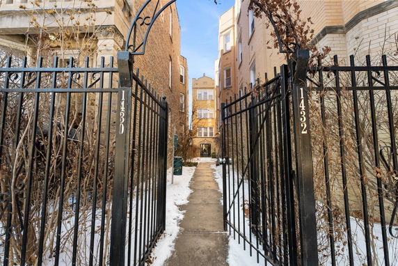Front view of a multi-story building with a pathway leading through a gated entrance.
