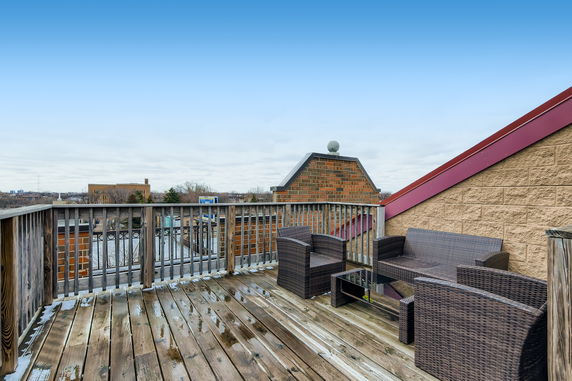 Rooftop with wicker furniture and wooden decking.