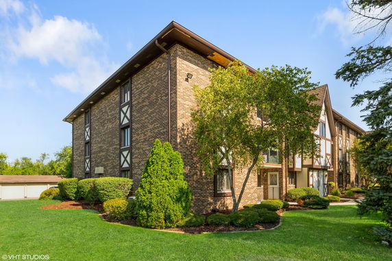 Front view of a three-story brick building with decorative patterns and a gable roof.