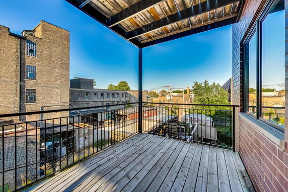 Panoramic view from a building's balcony showing surrounding buildings and trees.