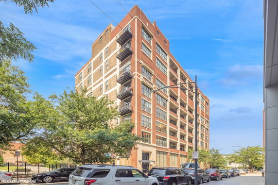 Front view of a multi-story brick building with large windows.