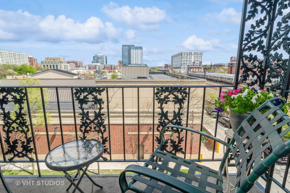 Balcony view with chairs, a table, and urban skyline in the background.