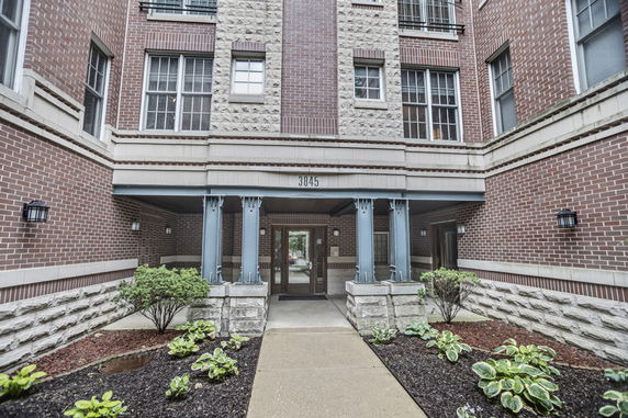 Front view of a multi-story residential building with brick façade and main entrance.