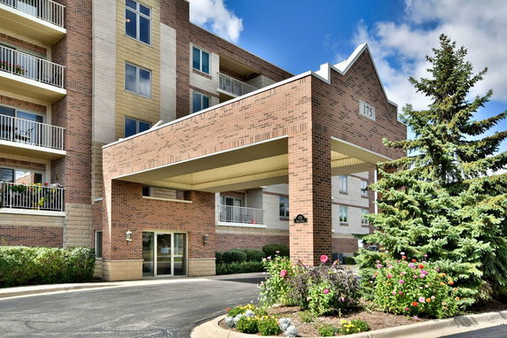 Front view of a multi-story brick building with balconies and an entrance canopy.