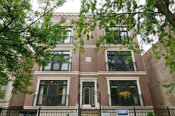 Front view of a multi-story brick residential building with balconies.