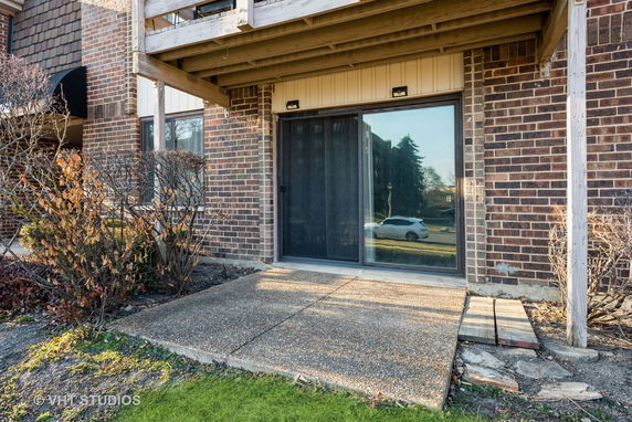 Exterior view of a brick building with a sliding glass door and a small patio area.