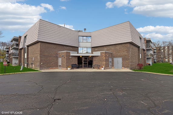 Front view of a multi-story brick building with a sloped roof and multiple balconies.