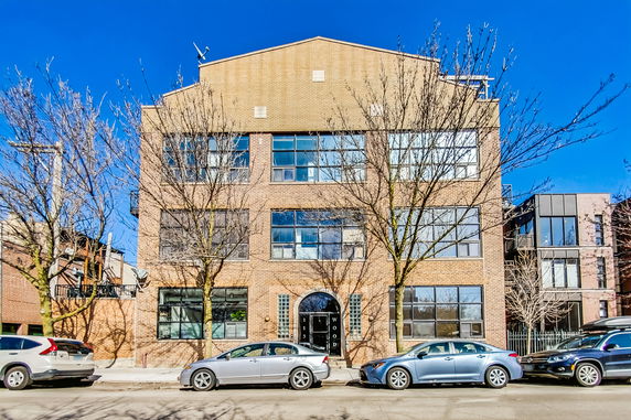 Front view of a multi-story brick building with large windows.