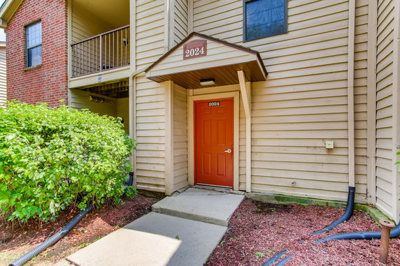 Front view of an apartment entrance with a red door and wooden siding.
