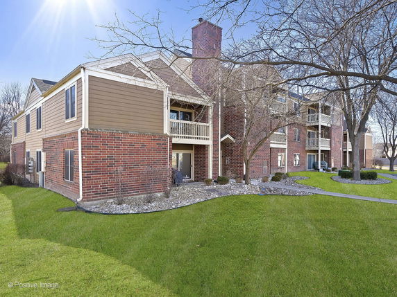Front view of a multi-story brick apartment building with balconies.