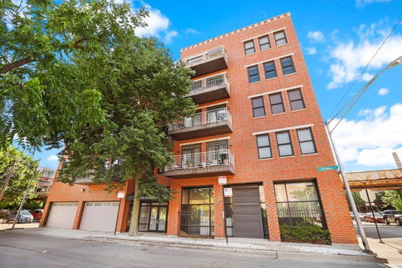 Front view of a multi-story brick residential building with balconies.