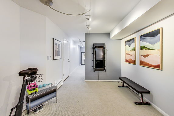 Indoor fitness area with exercise equipment and artwork on the walls.