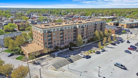 Front view of a multi-story brick apartment building with parking area in front.