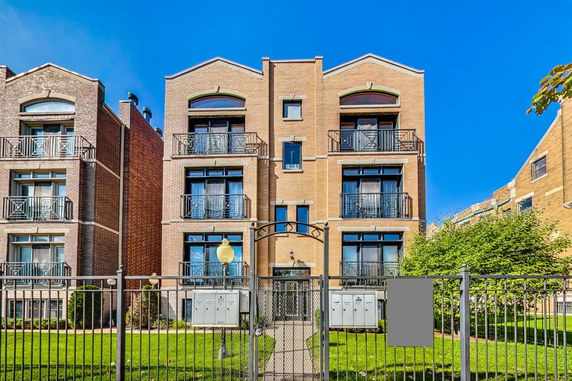 Front view of a multi-story brick apartment building with balconies.