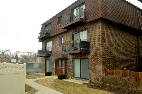 Front view of a multi-story brick apartment building with balconies.