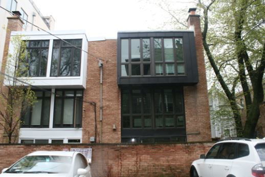 Front view of a modern two-story house with large windows and a brick facade.