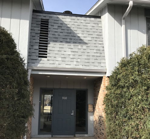 Front view of a building entrance with a shingled facade and a door labeled 908.