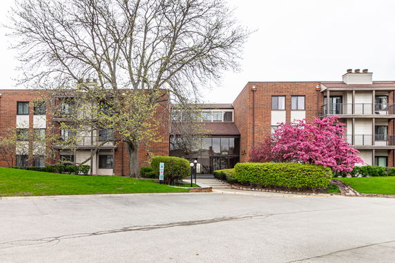 Front view of a multi-story apartment building with brick facade and balconies.