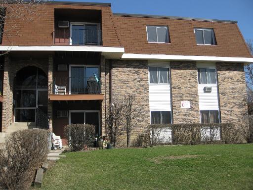Front view of a two-story brick building with a brown upper facade and multiple windows.