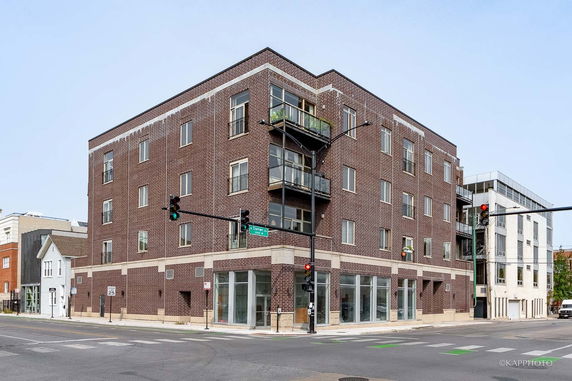 Front view of a multi-story brick building on a corner.