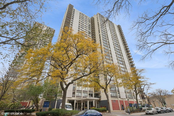 Front view of a tall residential building with multiple floors and large windows.