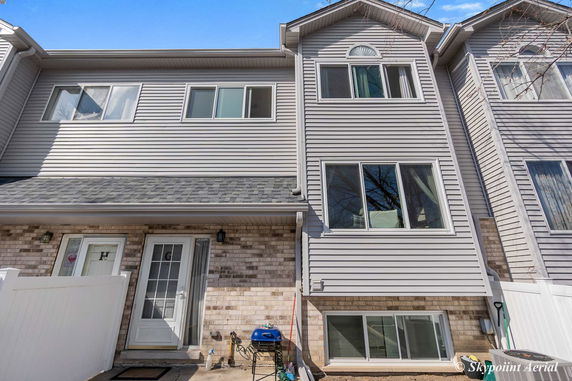 Front view of a multi-story townhouse with gray siding and brick accents.