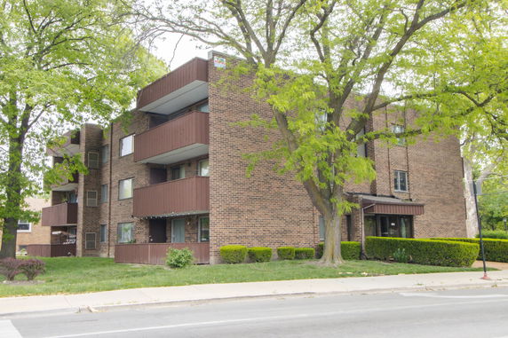 Front view of a multi-story brick apartment building with balconies.