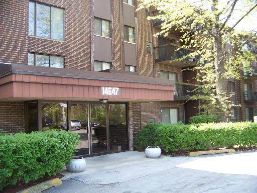 Front view of a multi-story brick apartment building with balconies.